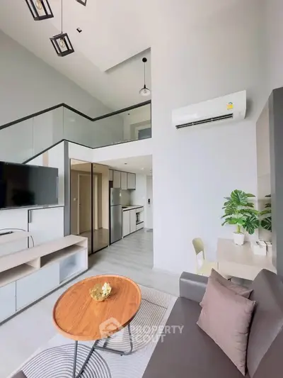 Modern living room with high ceiling and mezzanine, featuring sleek furniture and air conditioning.