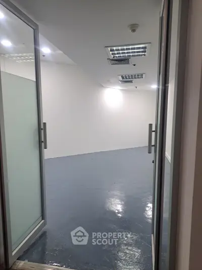 Spacious empty room with sliding glass doors and polished floor, ideal for office or studio setup.