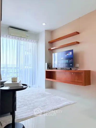 Modern living room with sleek TV setup and natural light from large windows.