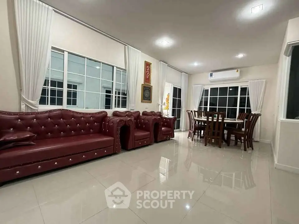 Spacious living room with elegant red leather sofas and dining area, featuring large windows and glossy tiled floors.