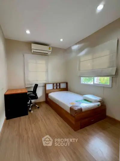Cozy bedroom with wooden flooring, single bed, desk, and air conditioning.