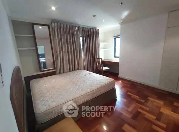 Spacious bedroom with hardwood floors and large window for natural light.