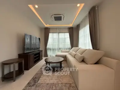 Elegant living room with modern sofa, large TV, and stylish lighting.