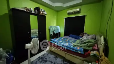 Cozy bedroom with vibrant green walls, air conditioning, and ample storage space.