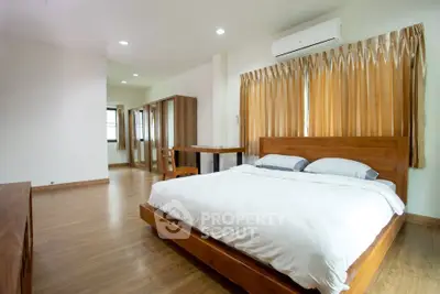 Spacious bedroom with wooden flooring and modern furnishings in a bright apartment.