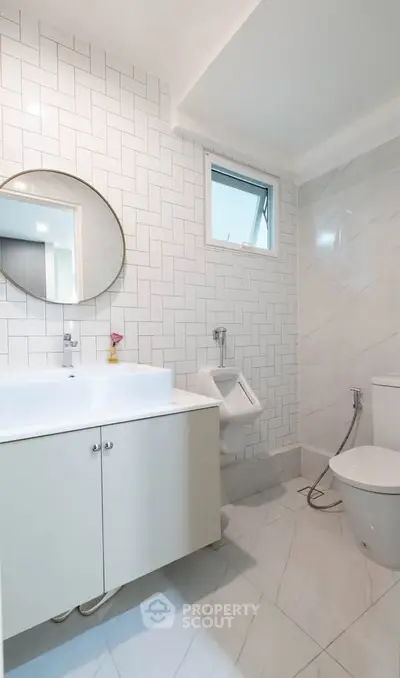 Modern bathroom with sleek white tiles and round mirror
