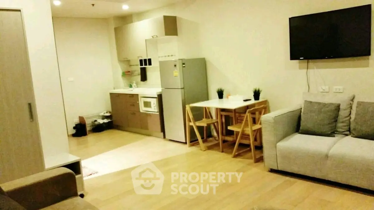 Modern open-plan living room with kitchen and dining area, featuring sleek furniture and appliances.