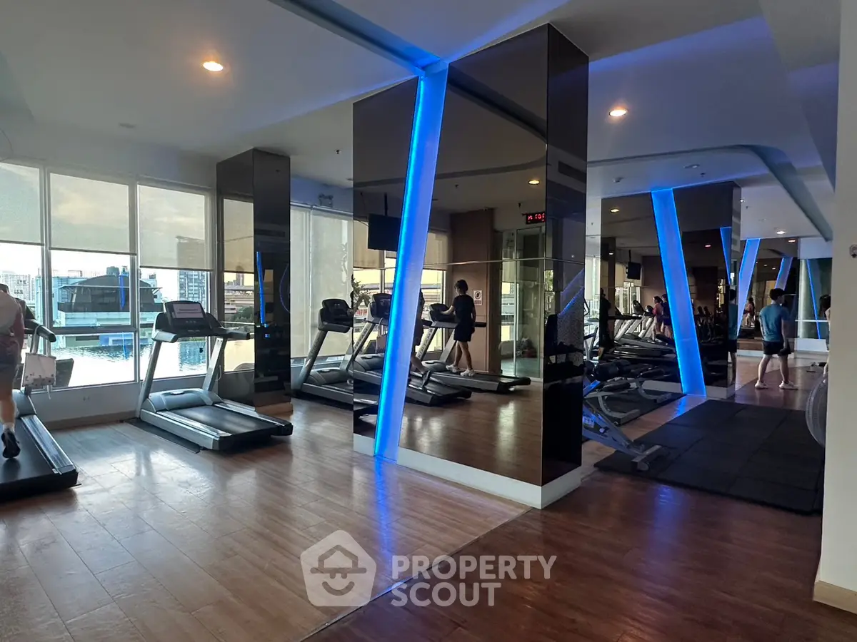 Modern gym with treadmills and mirrored walls in a high-rise building.