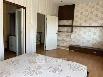 Spacious bedroom with elegant wallpaper and built-in shelves, perfect for modern living.