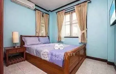 Cozy bedroom with wooden bed frame and blue walls, perfect for relaxation.