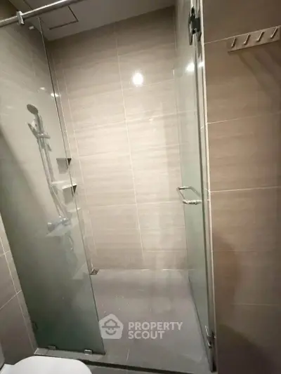 Modern bathroom with sleek glass shower enclosure and beige tiles