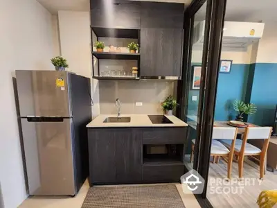 Modern compact kitchen with sleek cabinetry and stainless steel appliances in stylish apartment.