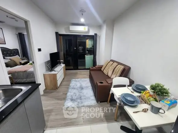 Modern open-plan living room with cozy dining area and stylish decor in a compact apartment.