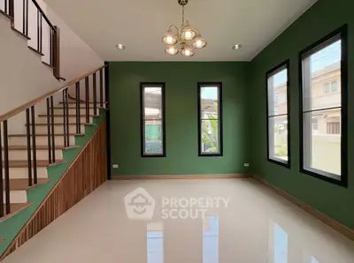 Spacious modern living room with elegant staircase and green accent wall
