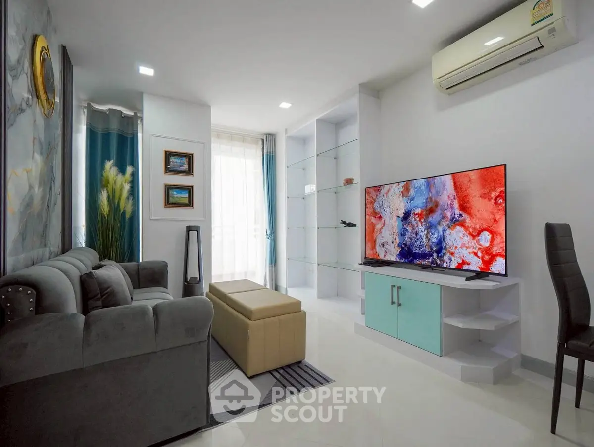 Modern living room with stylish decor, large TV, and comfortable seating in a bright apartment.