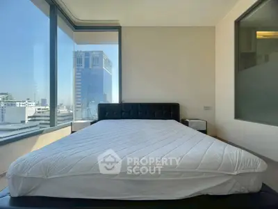 Modern bedroom with large windows offering stunning city views in a high-rise apartment.