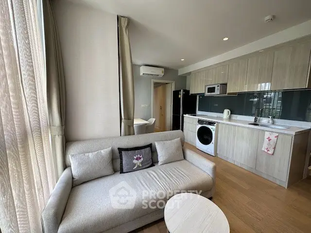 Modern living room with integrated kitchen, featuring sleek cabinetry and cozy seating area.