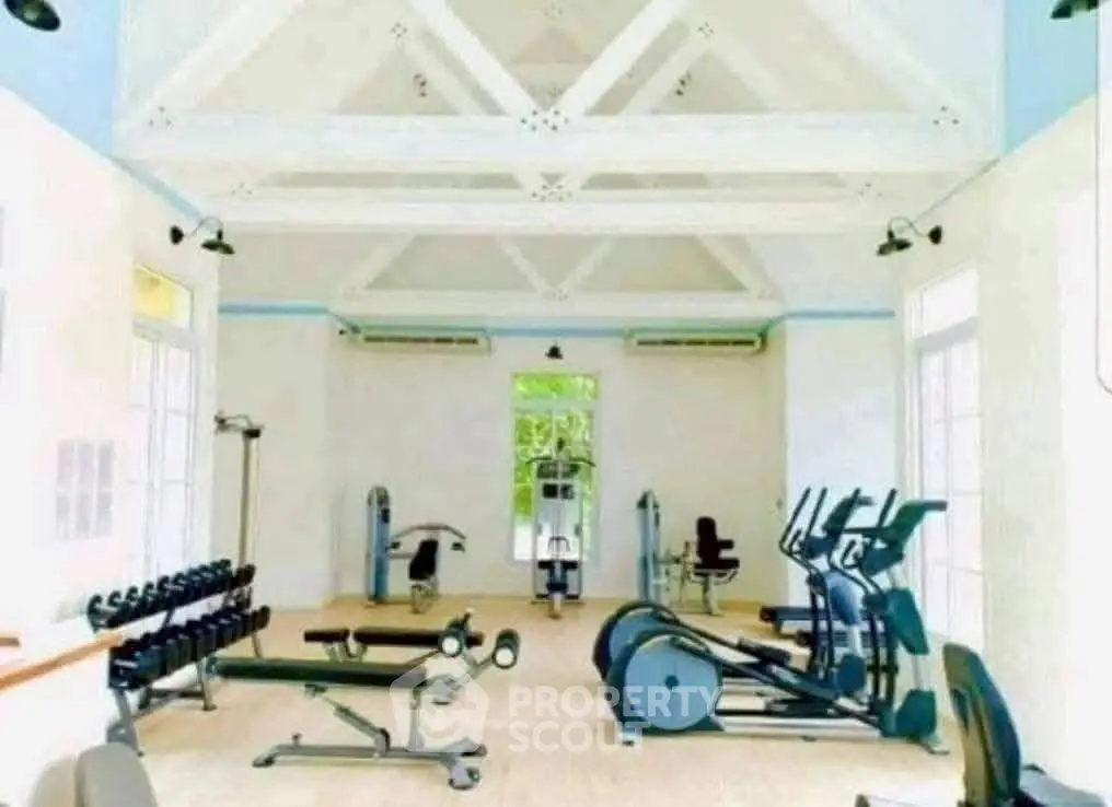 Spacious gym with modern fitness equipment and high ceilings in luxury property.