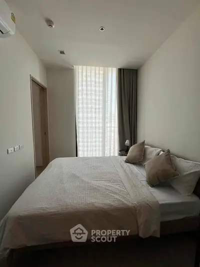 Modern bedroom with large window and minimalist decor in a stylish apartment.