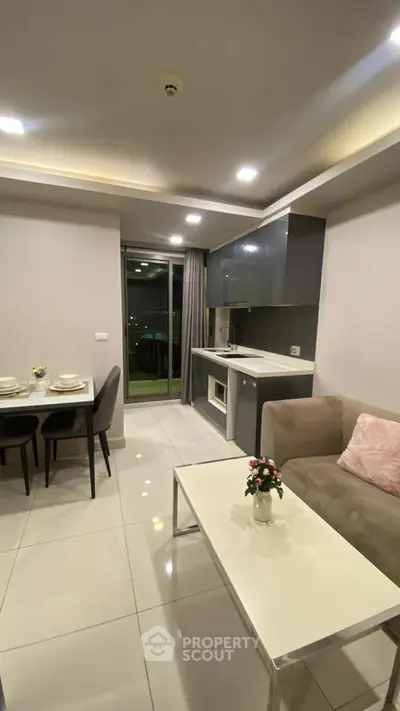 Modern open-plan living room with sleek kitchen and dining area, featuring contemporary furniture and stylish decor.