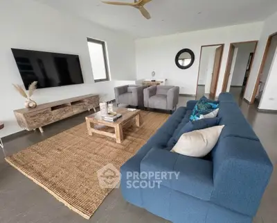 Spacious modern living room with stylish furniture and large TV, perfect for relaxation and entertainment.