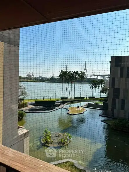 Stunning waterfront view from a modern building balcony, featuring lush greenery and serene water features.