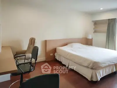 Spacious bedroom with wooden flooring and modern furniture
