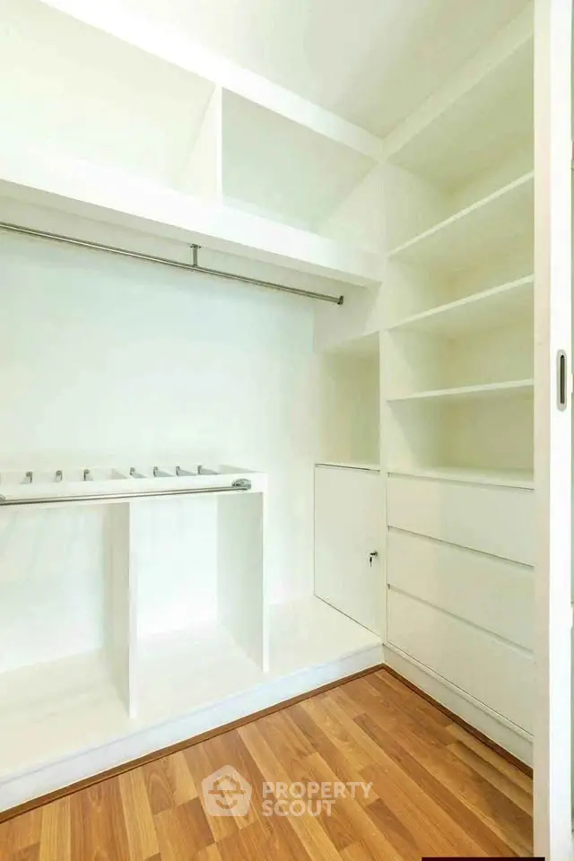 Spacious walk-in closet with wooden flooring and ample shelving.