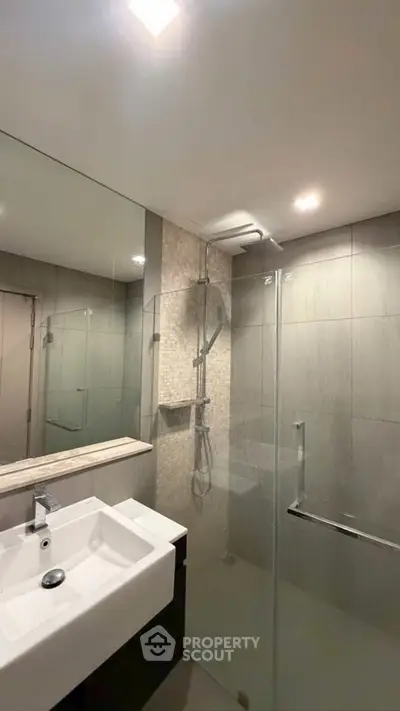 Modern bathroom with sleek shower and elegant sink in a contemporary home.