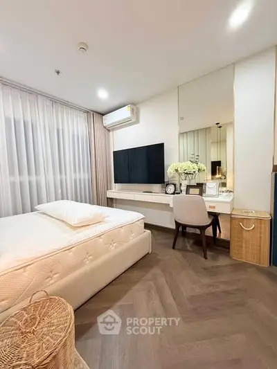 Modern bedroom with elegant decor and large TV, featuring a cozy workspace and stylish flooring.