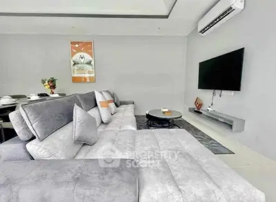 Modern living room with sleek gray sofa and wall-mounted TV, perfect for relaxation and entertainment.