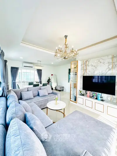 Luxurious living room with elegant chandelier and plush gray sofas, perfect for modern comfort and style.