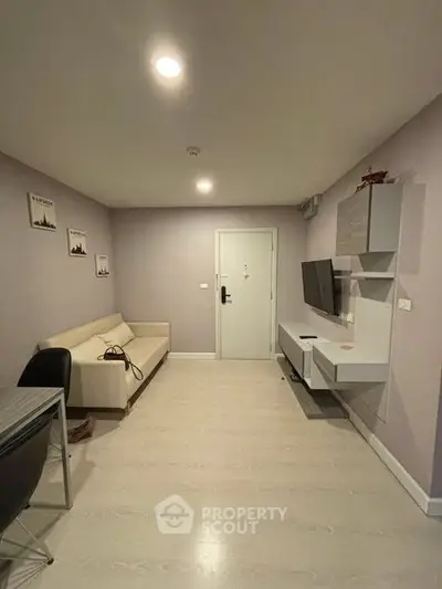 Modern living room with sleek furniture and wall-mounted TV in a cozy apartment.