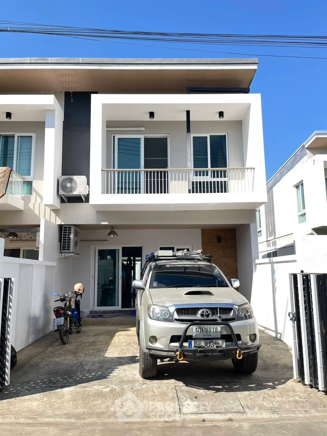 Modern townhouse with driveway and parked SUV in sunny neighborhood