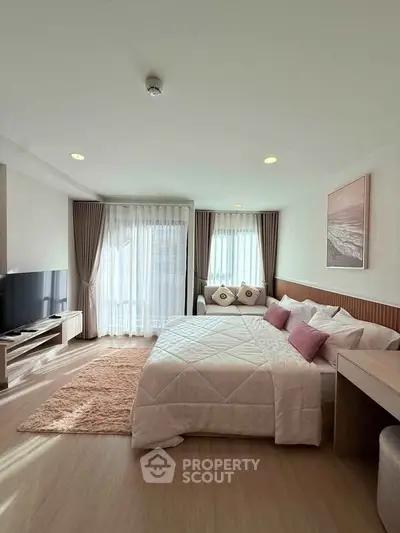 Spacious bedroom with modern decor and large windows for natural light.