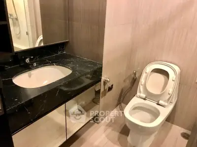 Modern bathroom with sleek black marble countertop and elegant fixtures.