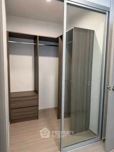 Spacious walk-in closet with modern wooden shelving and sliding mirror doors.
