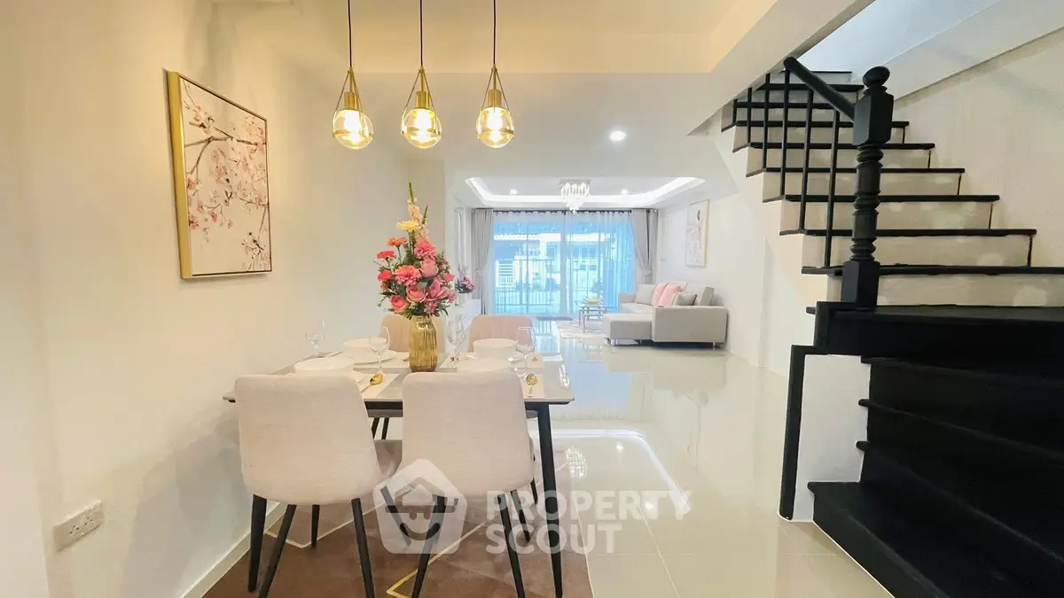 Elegant open-plan living and dining area with modern decor and staircase