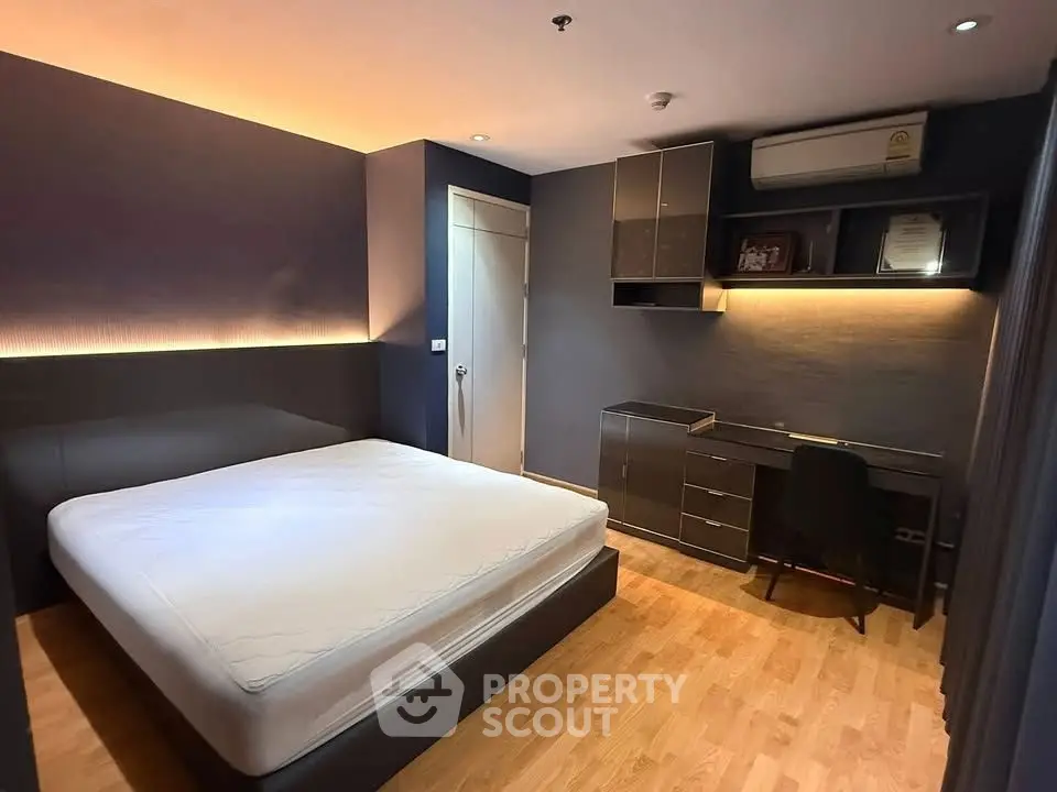 Modern bedroom with sleek design, featuring a comfortable bed and stylish workspace.