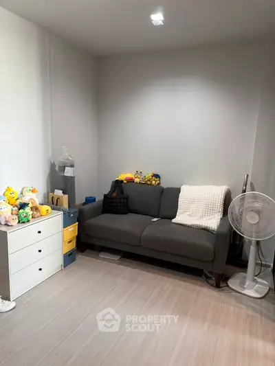 Cozy living room with gray sofa and plush toys, perfect for relaxation.