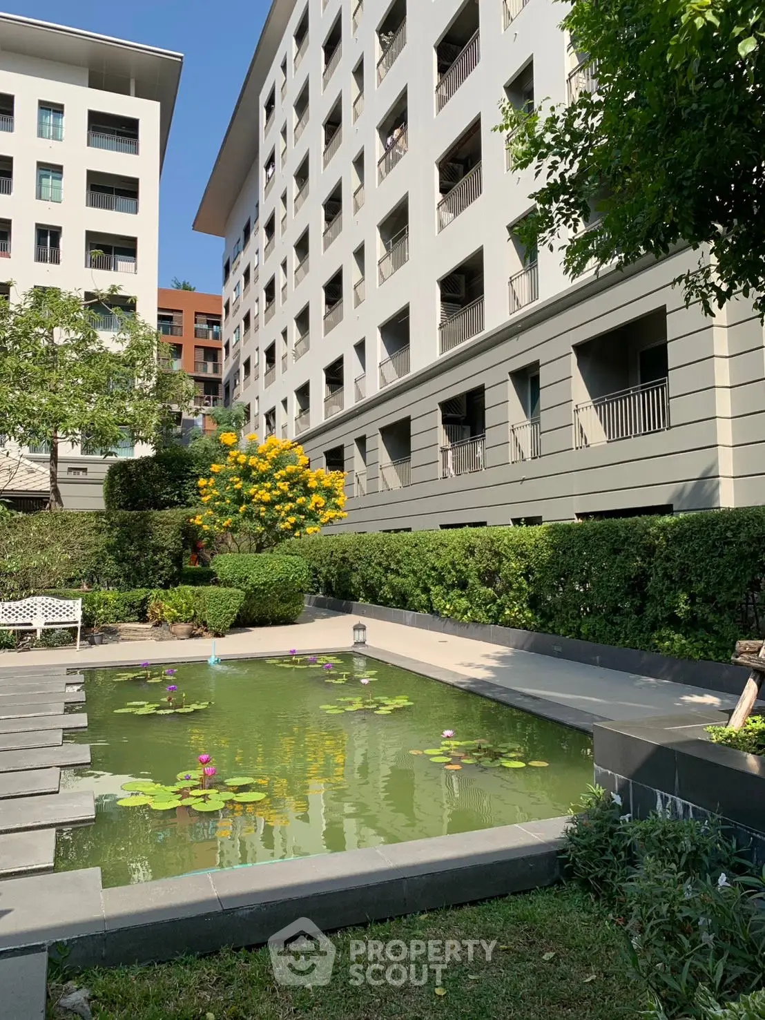 Modern apartment building with serene garden pond and lush greenery