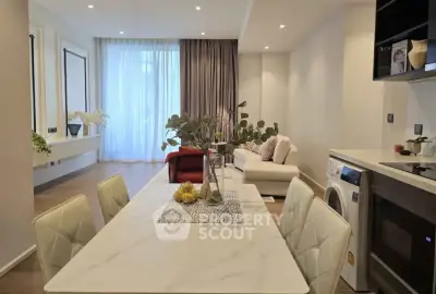 Modern open-plan living room with elegant dining area and washing machine in stylish apartment.