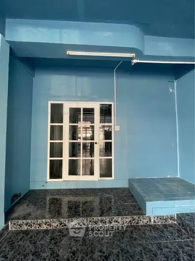 Spacious blue interior with tiled flooring and glass doors, ideal for creative renovation.