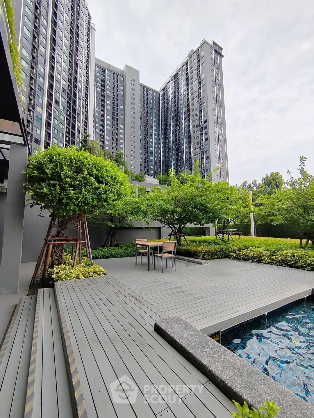 Modern high-rise building with lush garden and poolside deck, perfect for urban living.