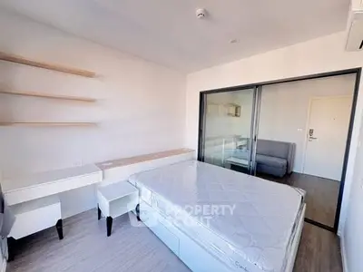Modern bedroom with minimalist design and sliding glass doors leading to a cozy living area.