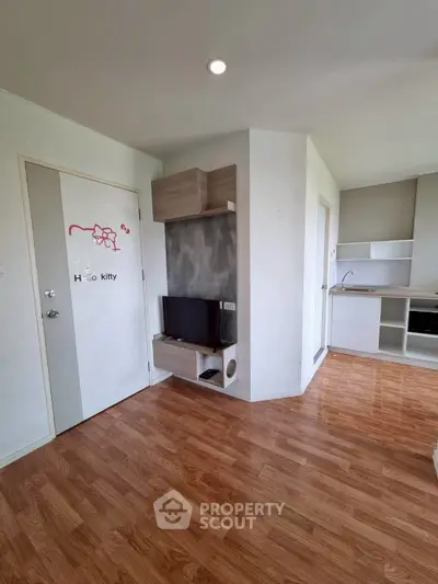 Modern apartment interior with stylish kitchen and cozy living area, featuring wood flooring and sleek design.