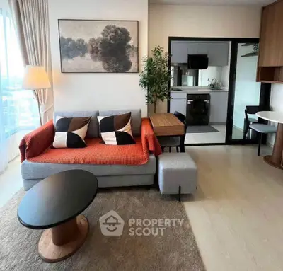 Modern living room with stylish decor and open kitchen layout, featuring cozy seating and natural light.