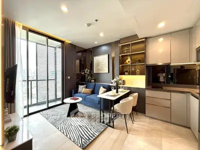Modern open-layout living room with kitchen, featuring stylish decor and large windows for natural light.