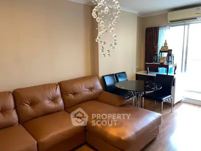 Spacious living room with leather sofa and modern chandelier in a cozy apartment.