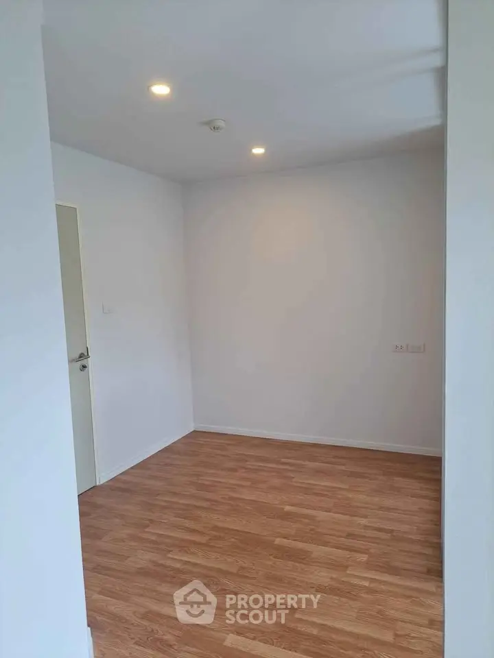 Spacious empty room with wooden flooring and white walls, ideal for customization.